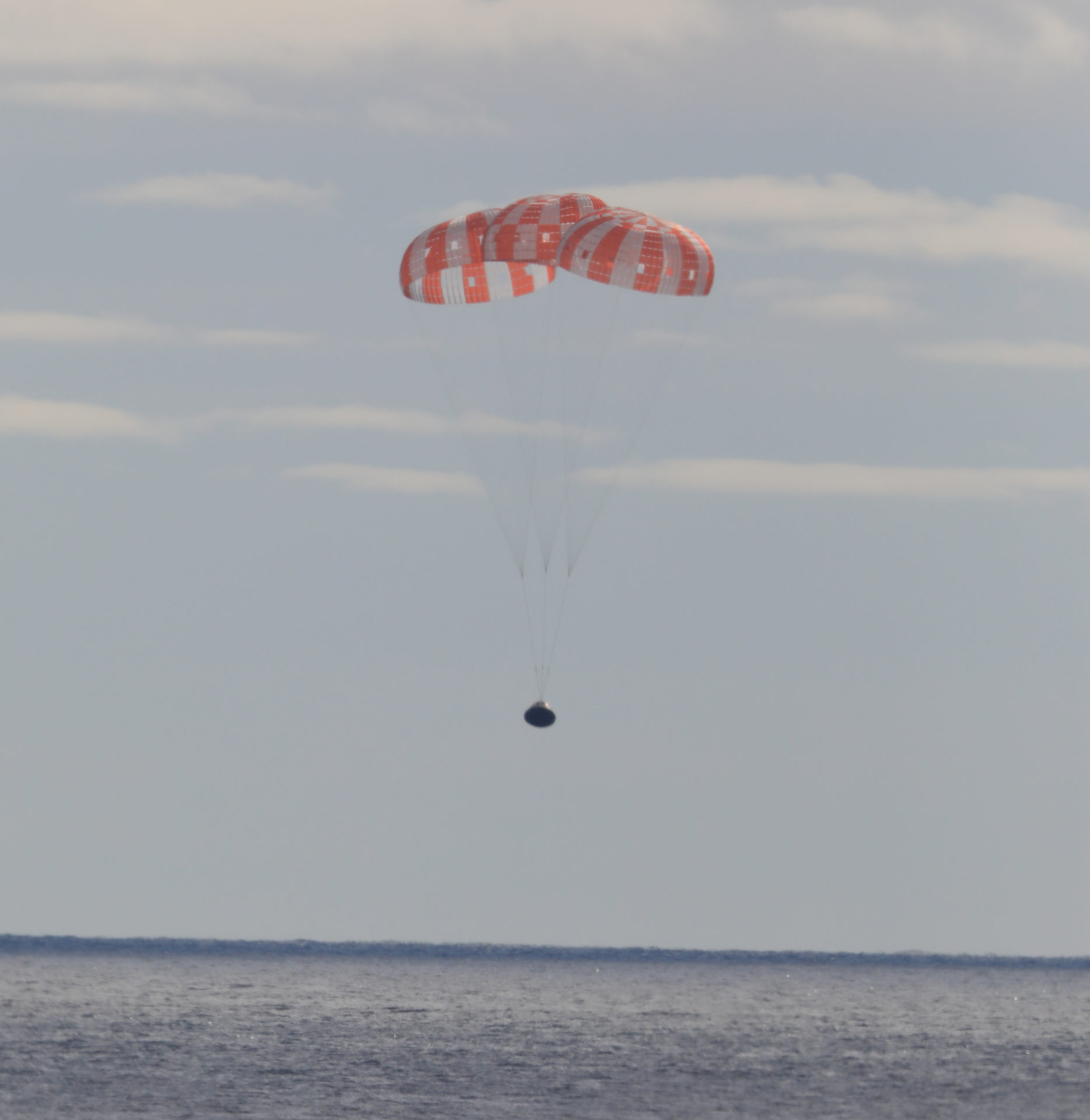 La capsule Orion descend vers l'océan Pacifique sous ses 3 parachutes
